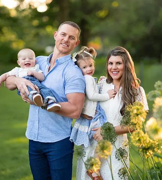 Greg Harris holding his son, with his wife and daughter, outdoors